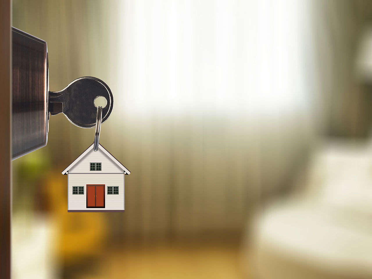 Nøgle i lås med et lille hus som nøglering