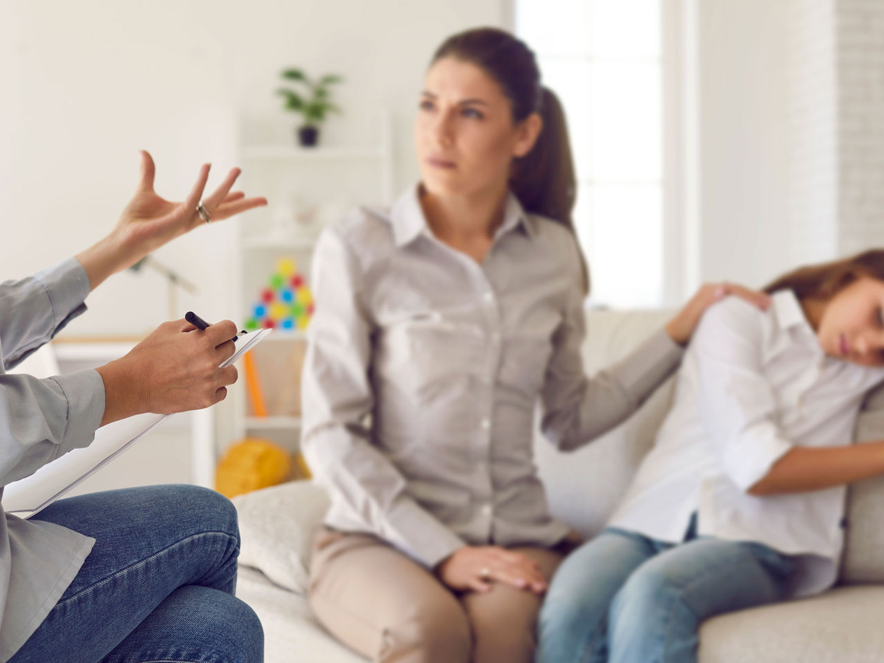 Mor med hånden på sin datters skulder mens hun modtager rådgivning