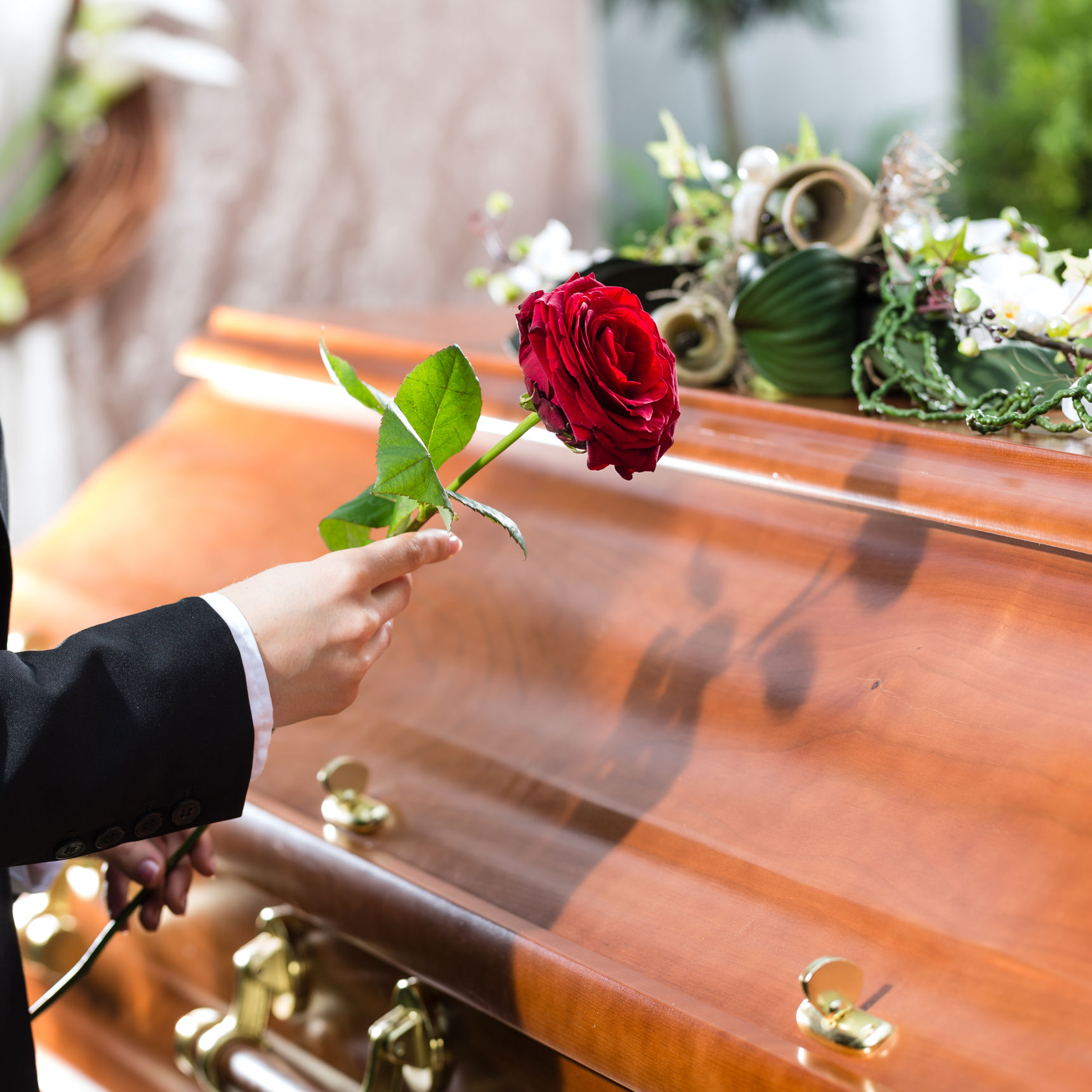 Person med rose ved kiste
