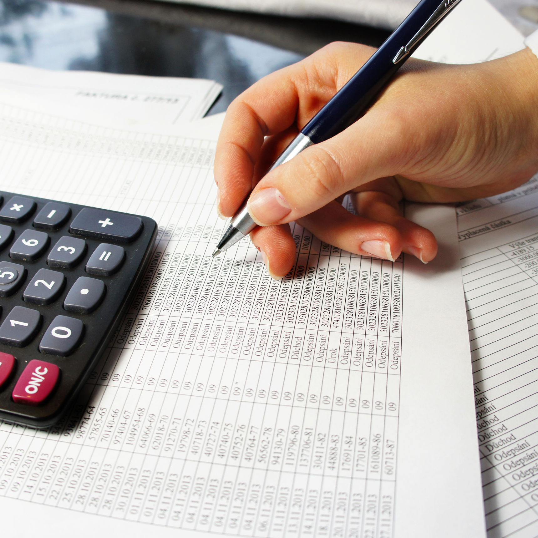 Hånd med kuglepen der laver regnskab