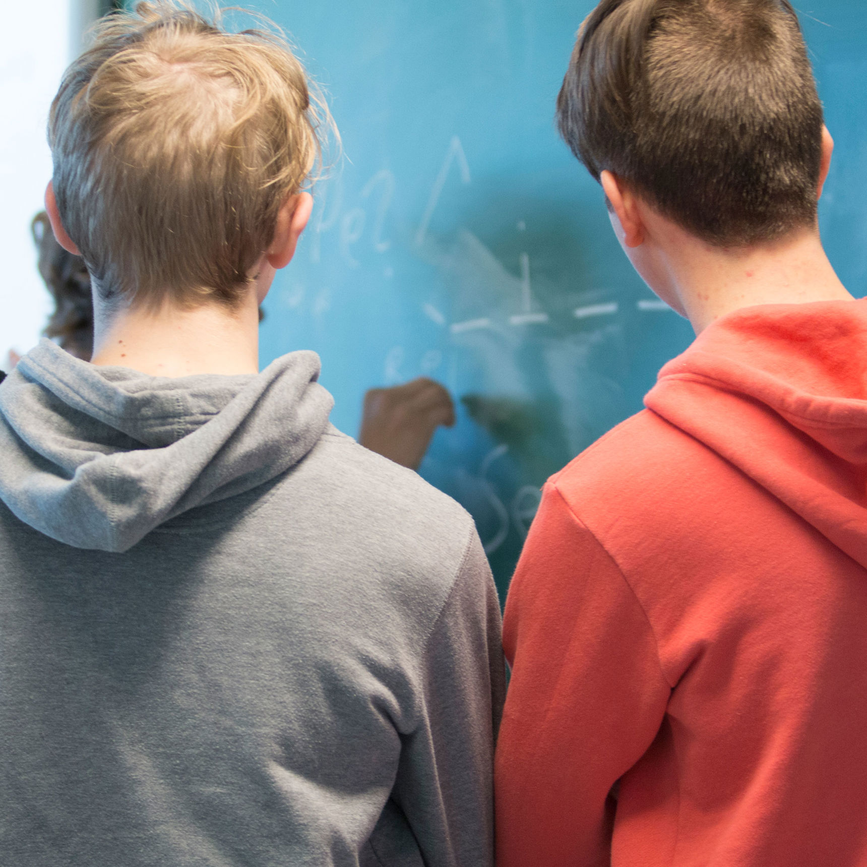 Tre skolelever med ryggen til der skriver på en tavle // Foo: Colourbox
