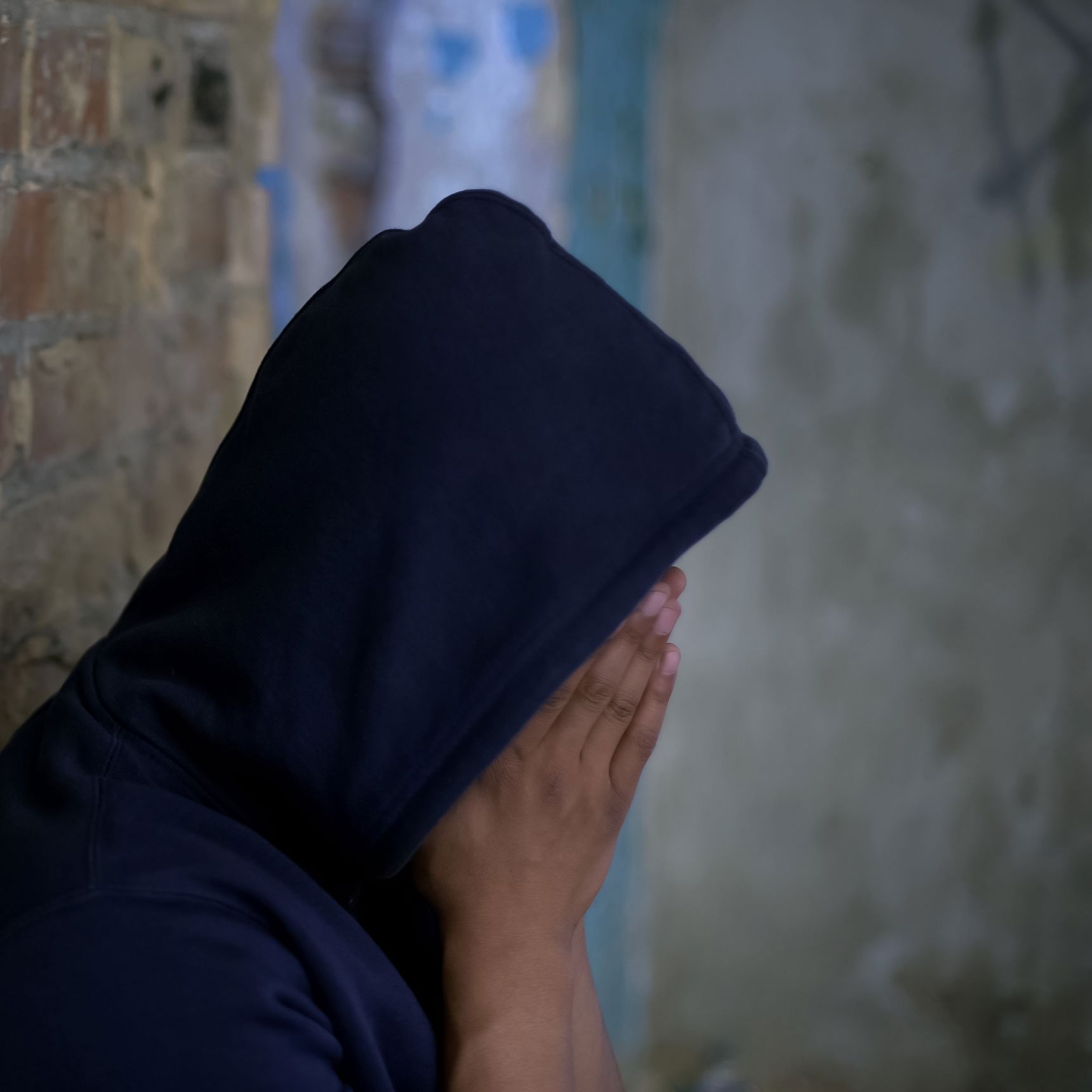 Mand med hætte over hovedet og hænderne for munden