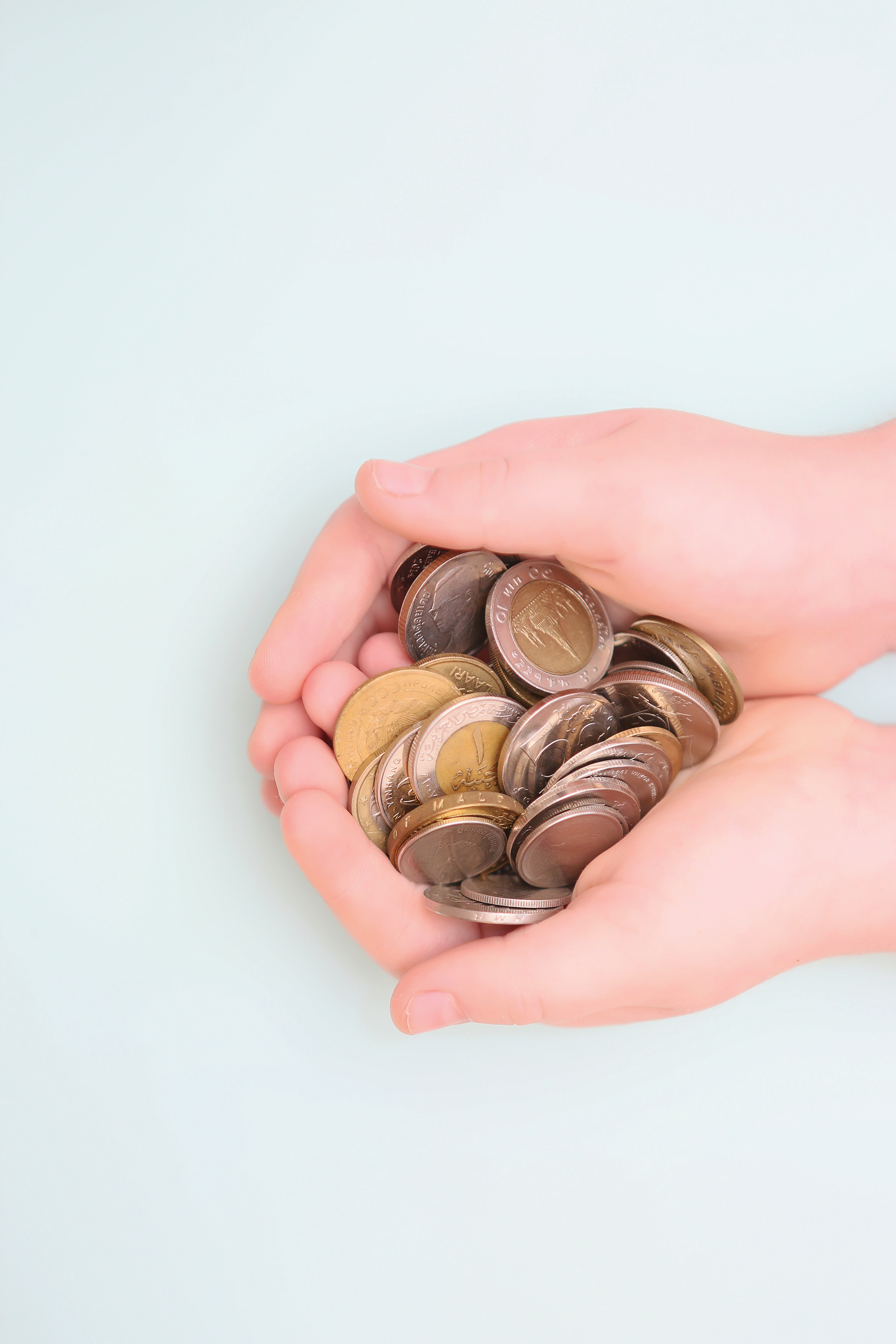 Hænder der holder en masse mønter