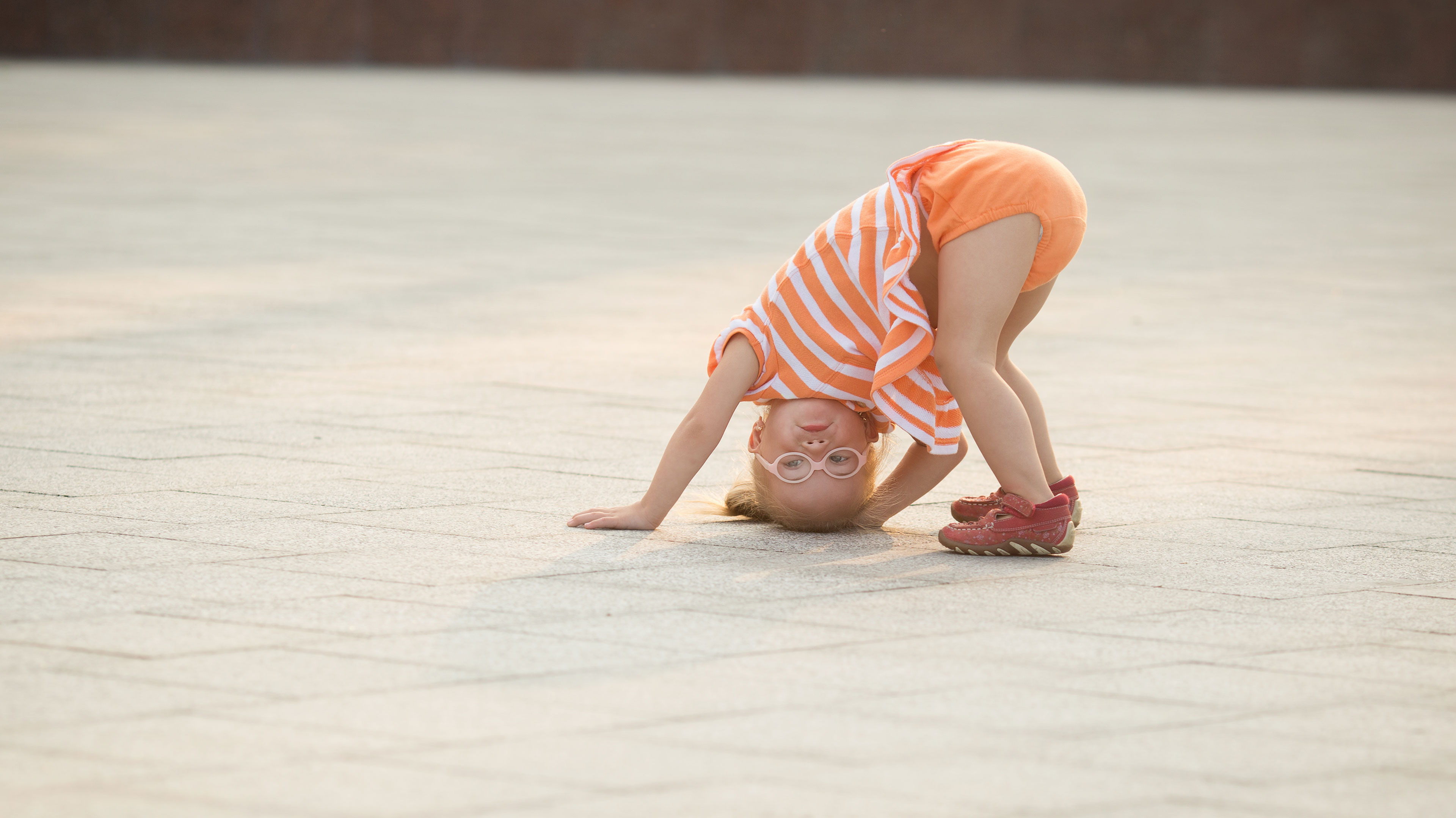Lille pige med briller der har hovedet nedad // Foto: Coloubox