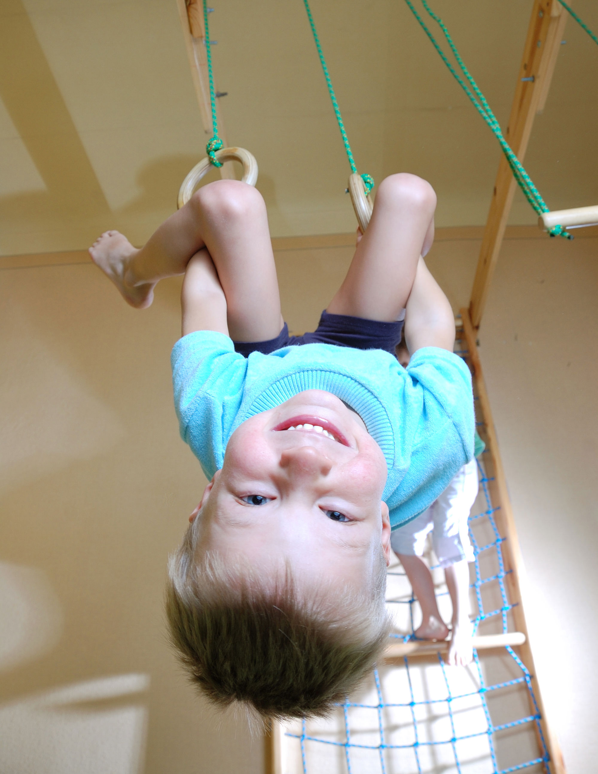 Dreng der sviger sig i ringe i en gymnastiksal