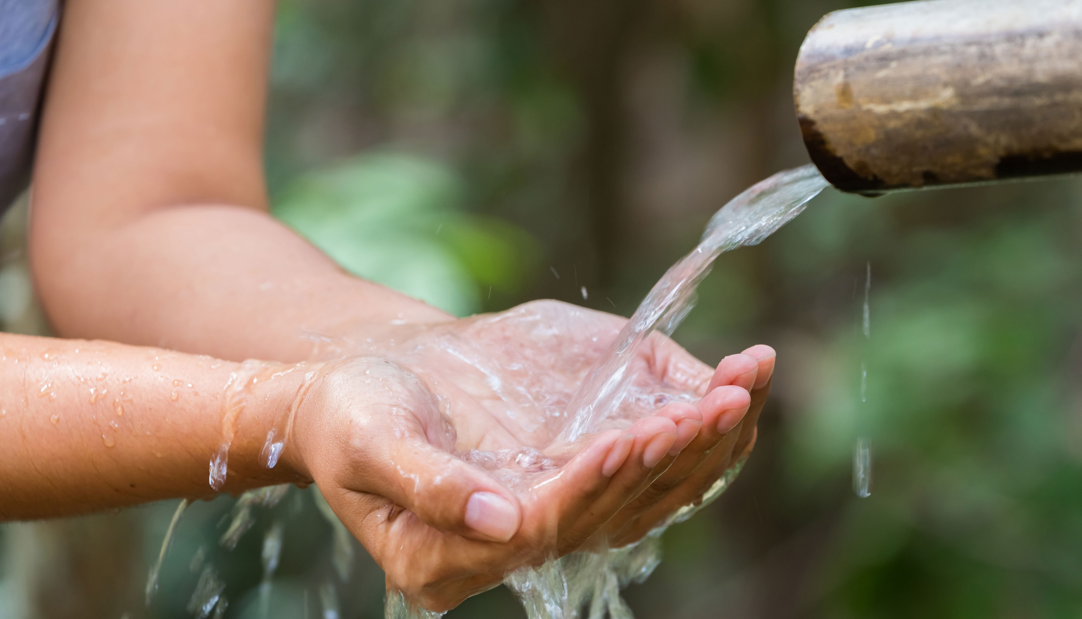 Hænder tager imod vand strømmende fra rør
