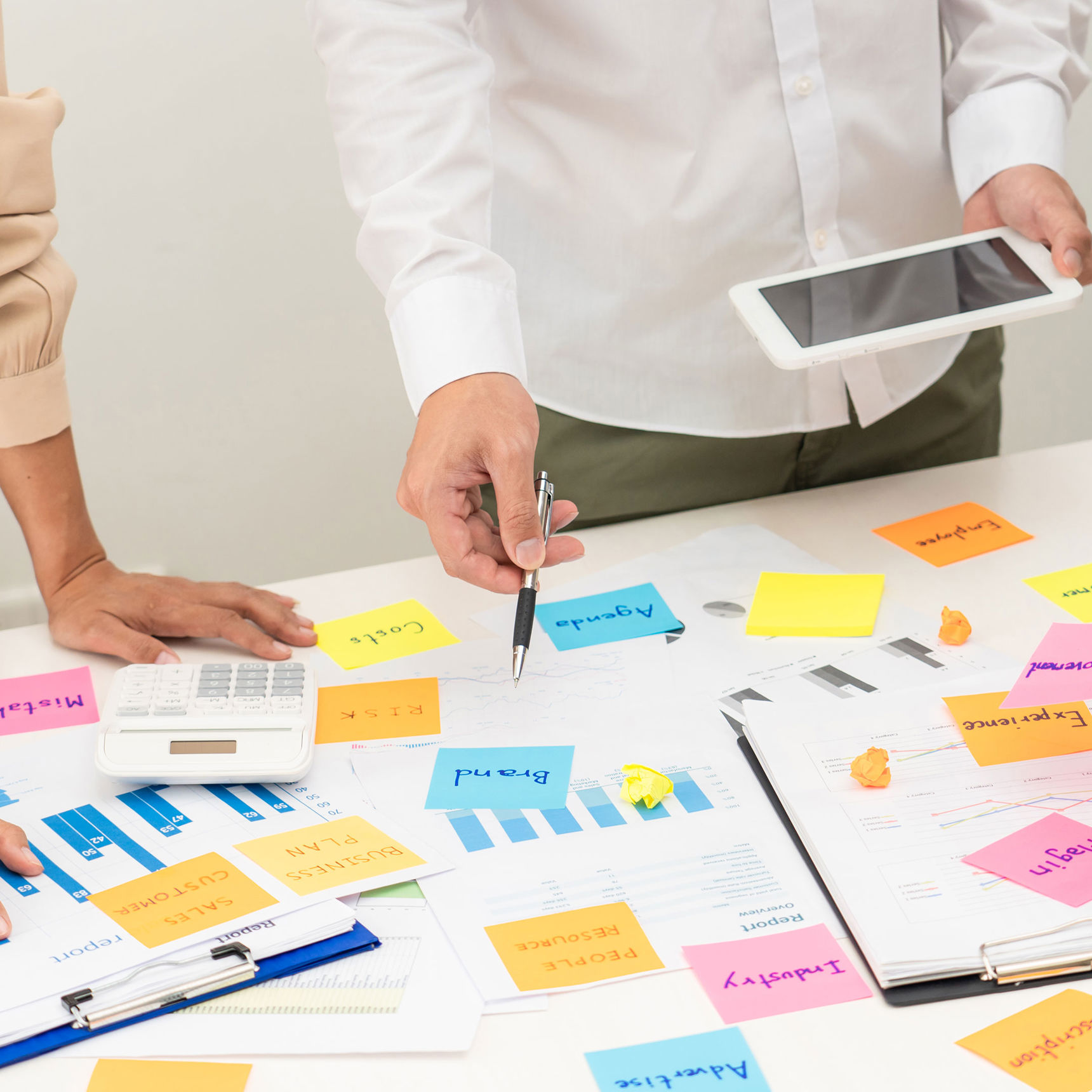 Folk stående over et skrivebord med masser af post-it sedler // Foto: Colourbox