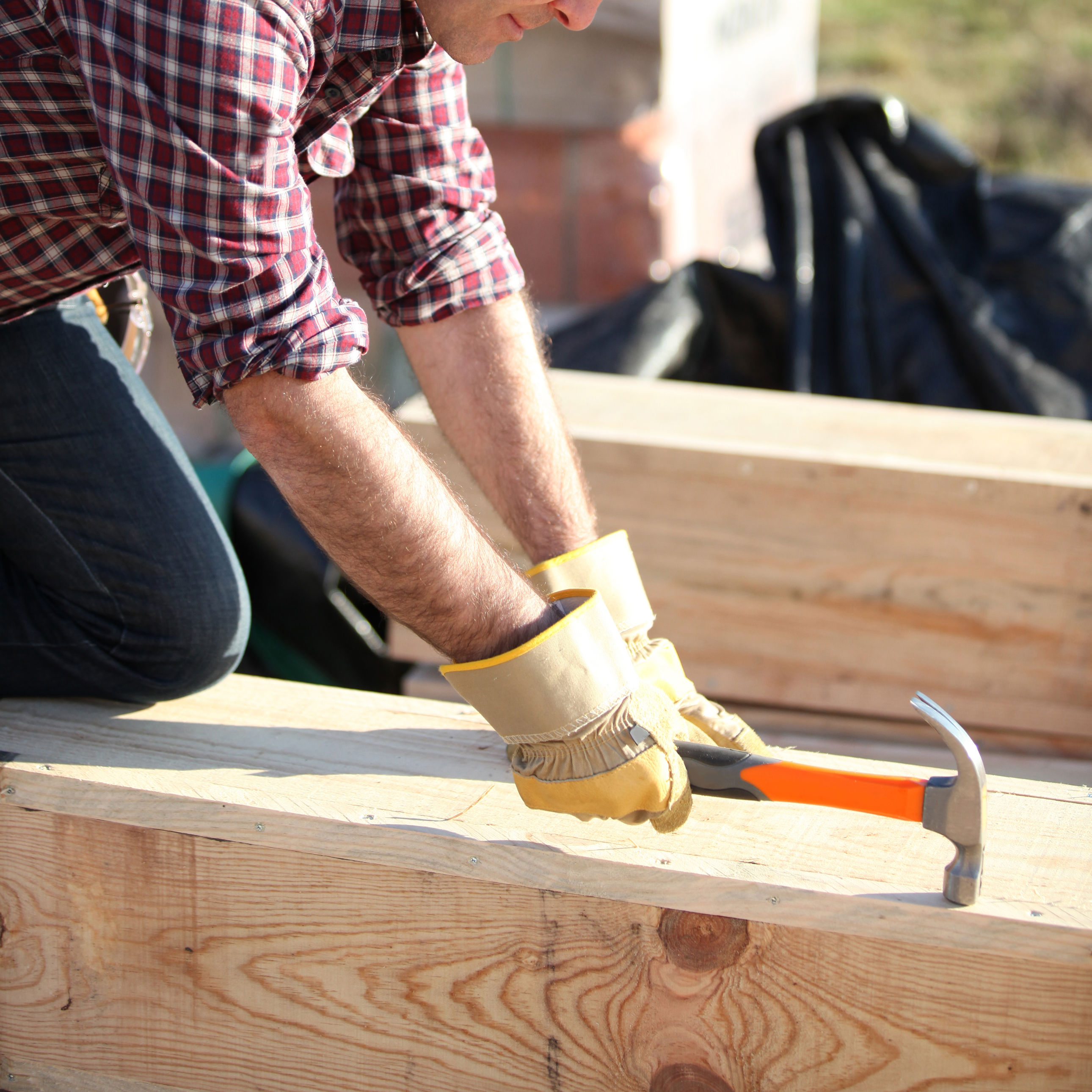 Håndværker slå søm i træ på byggeplads